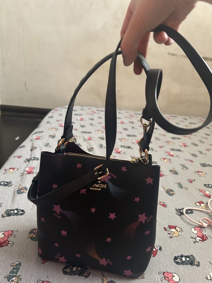 Coach Black Star Print Bucket Bag (Category: Luxury Bags & Wallets) located in Manila. Submitted by lottiepot (Listing ID 1457909001, Image 3). Description: - Adorable black Coach bucket bag - Features a fun pink star print - Includes both a top handle and a crossbody strap for versatile carrying - Elegant gold hardware details - Secure zipper closure - Ideal for your everyday essentials and style.