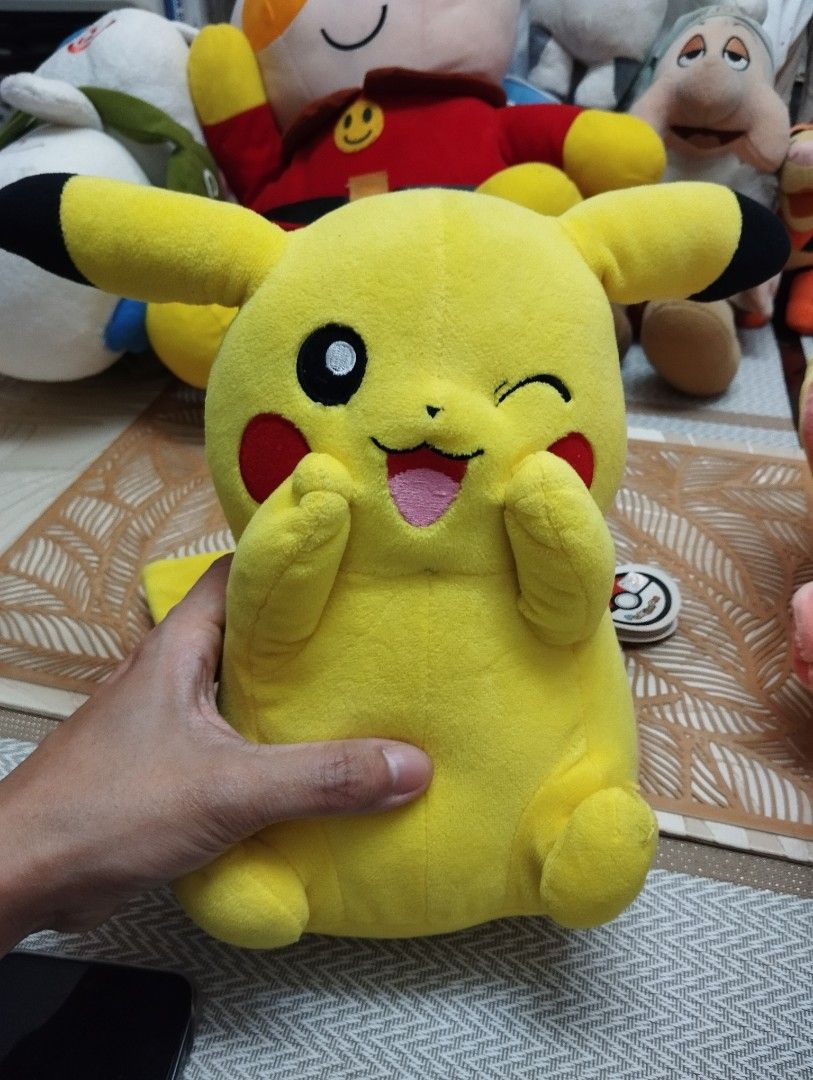 Cute Winking Pikachu Plush Toy (Category: Plushies & Soft Toys) located in Manila. Submitted by reiolshoppe (Listing ID 1457977434, Image 1). Description: - Adorable Pikachu plush toy - Features a cute winking expression - Holding its cheeks - Soft and cuddly material - Ideal for Pokémon fans and collectors - Perfect for display or playtime.