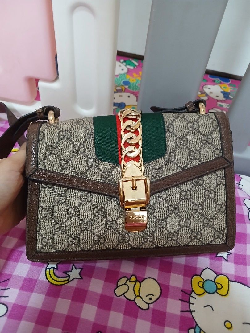 Gucci Sylvie Shoulder Bag (Category: Luxury Bags & Wallets) located in Manila. Submitted by pretty0099 (Listing ID 1457967405, Image 1). Description: - Classic Gucci shoulder bag - Coded - Iconic GG monogram canvas - Brown leather trim and strap - Gold-tone hardware with chain detail - Green and red web stripe accent - Detachable shoulder strap included - Versatile for everyday or special occasions.