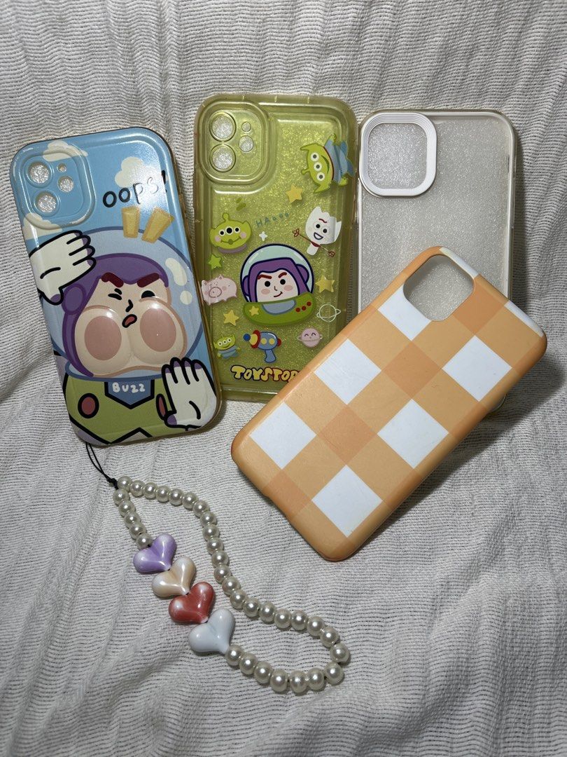 Iphone 11 Phone Case Bundle (Category: Cases & Sleeves) located in Manila. Submitted by prima_onda (Listing ID 1457963852, Image 1). Description: - iPhone 11 phone case bundle - Features designs inspired by Buzz Lightyear and Toy Story aliens - Includes a stylish orange checkered case - Comes with a pearl strap adorned with heart charms - Offers protection and a personalized look for your iPhone 11.