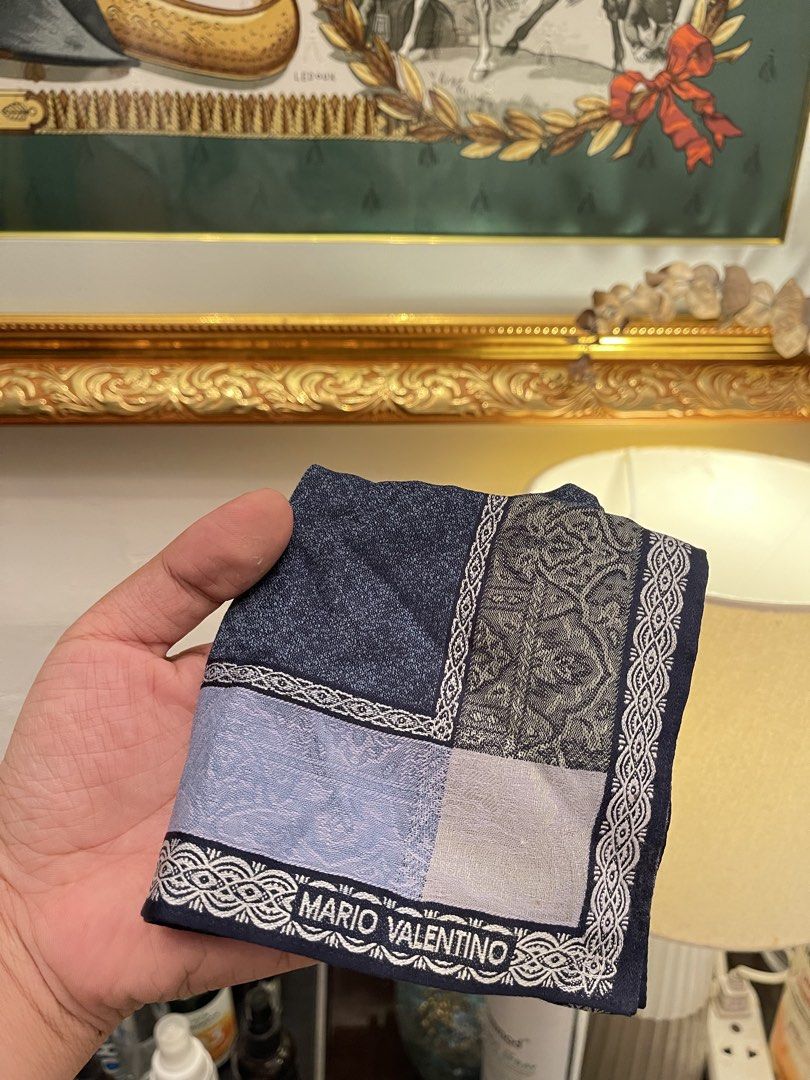Mario Valentino pocket square (Category: Luxury Bags & Wallets) located in Marilao. Submitted by wardrovearchives (Listing ID 1458053112, Image 1). Description: - Classic Mario Valentino pocket square - Features dark blue, light blue, and grey patterns - Branded border with the Mario Valentino name - Perfect accessory to elevate your look - Approximate dimensions: 16x16 inches.