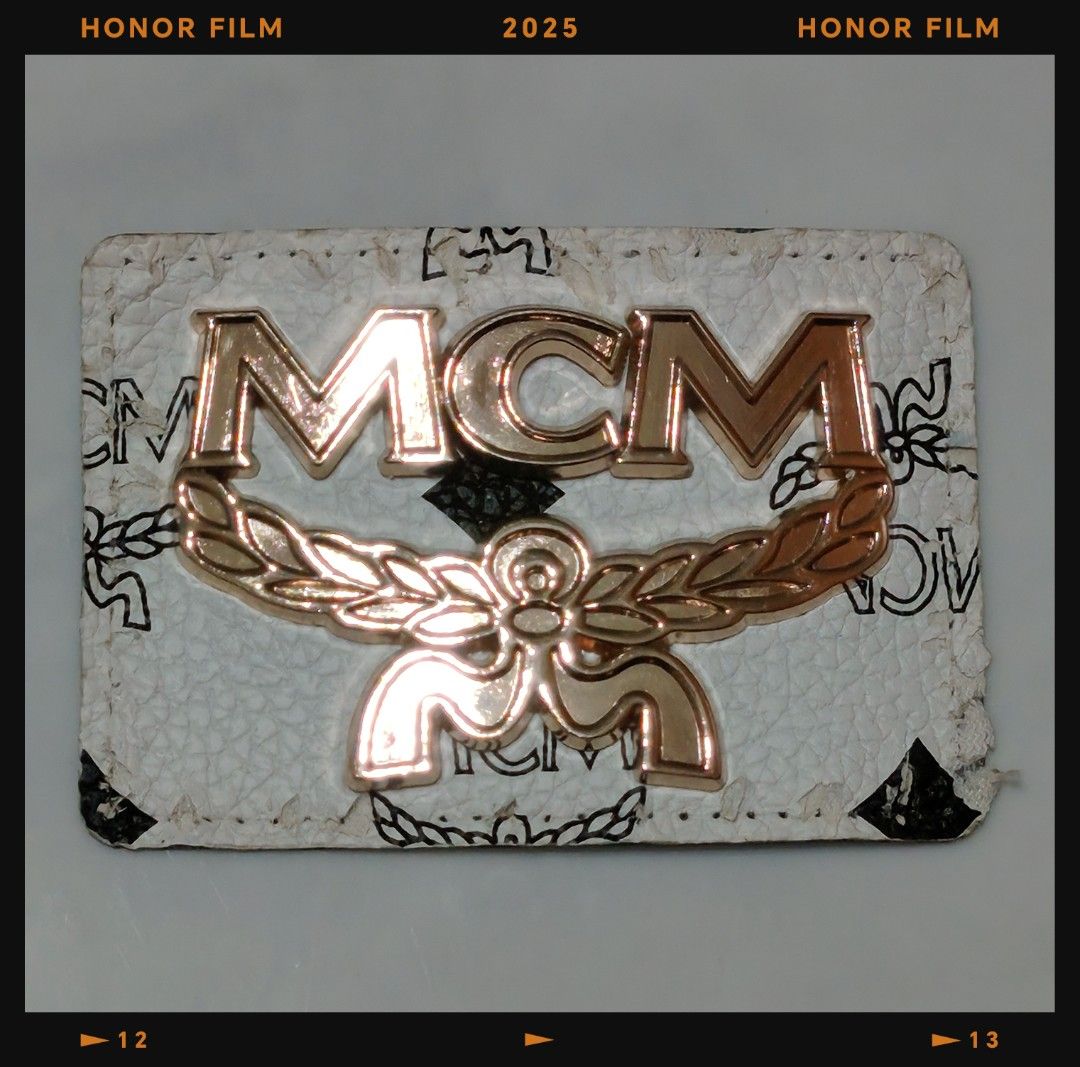 MCM logo patch (Category: Accessories) located in Singapore. Submitted by COOLajiCharlie (Listing ID 1458093086, Image 1). Description: - Authentic MCM logo patch - Features the signature gold-toned MCM logo - Classic white Visetos print - Ideal for customizing bags, apparel, or accessories - Unisex design - Meetup available at Pasir Ris Drive 6 Carpark.