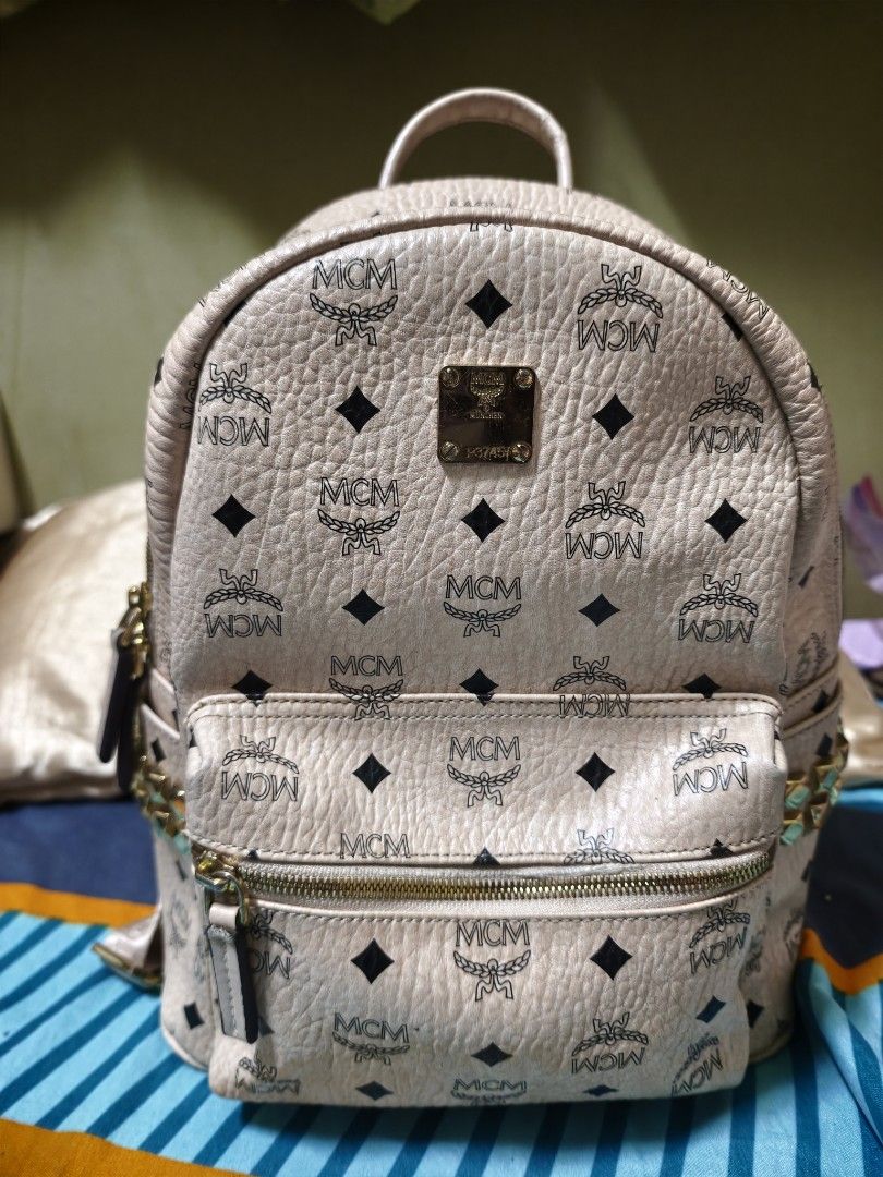 MCM Stark Backpack MM Beige Visetos Studded (Category: Luxury Bags & Wallets) located in Makati City. Submitted by manririn (Listing ID 1458049217, Image 1). Description: - MCM Stark Backpack - Classic Beige Visetos Print - 16k Gold Studs on side Pocket - Adjustable Straps - Main Compartment + Inner Pocket - Ideal for Everyday Use ISSUE: The clothing is damaged around the small front zipper, with visible tearing and fraying of the fabric along th