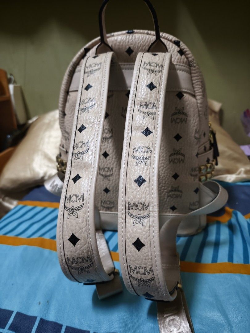 MCM Stark Backpack MM Beige Visetos Studded (Category: Luxury Bags & Wallets) located in Makati City. Submitted by manririn (Listing ID 1458049217, Image 2). Description: - MCM Stark Backpack - Classic Beige Visetos Print - 16k Gold Studs on side Pocket - Adjustable Straps - Main Compartment + Inner Pocket - Ideal for Everyday Use ISSUE: The clothing is damaged around the small front zipper, with visible tearing and fraying of the fabric along th