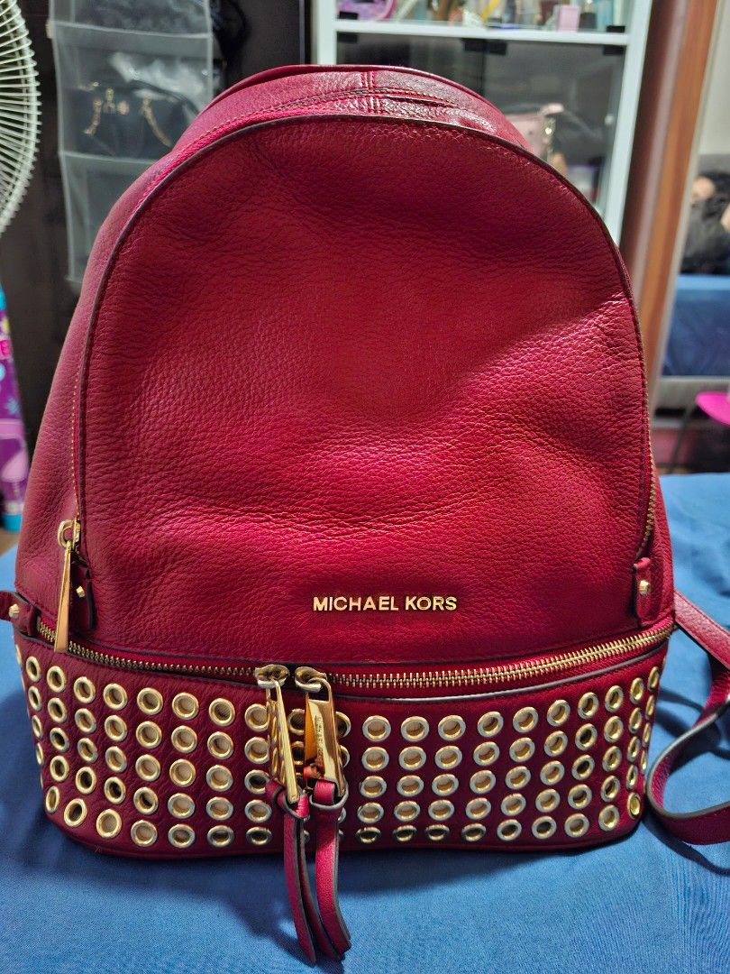 Michael Kors Red Leather Studded Backpack (Category: Backpacks) located in Manila. Submitted by yanakolekzione (Listing ID 1458063864, Image 1). Description: - Authentic Michael Kors backpack in a striking red color. - Crafted from genuine leather with elegant gold stud accents on zippers. - Interior boasts multiple compartments, including a secure zippered pocket. - Adjustable straps for a comfortable, customized fit. - Please note: Minor signs 
