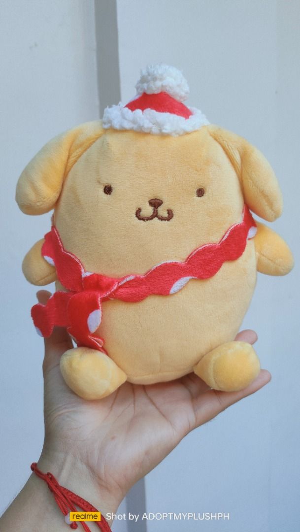 Sanrio Pompompurin Holiday plush (Category: Plushies & Soft Toys) located in Taguig. Submitted by adopt.my.plush.ph (Listing ID 1457903409, Image 1). Description: Pompompurin holiday plush toy featuring the Sanrio character dressed in a small Santa hat and a red-and-white wavy scarf. Manufacturer: E-STRONG / 长亿玩具 (Changsha Changyi Toys Co., Ltd.).