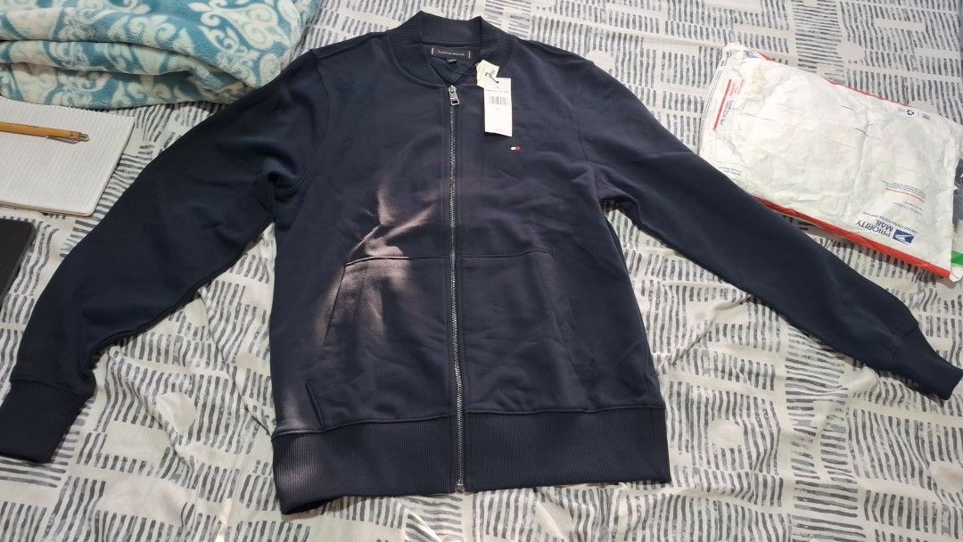 Tommy Hilfiger Navy Blue Bomber Jacket (Category: Coats, Jackets and Outerwear) located in Quezon City. Submitted by mgdeclutters (Listing ID 1457983720, Image 3). Description: - Navy blue Tommy Hilfiger bomber jacket - Full zip front with pockets - Ribbed cuffs and hem for a snug fit - Small Tommy Hilfiger flag logo on the chest - Ideal for everyday casual wear - Brand new with tag still attached.
