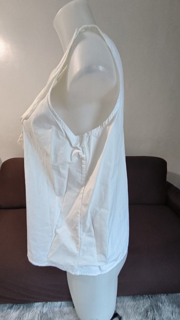 White Sleeveless Top with Ruffle Detail (Category: Sleeveless) located in Antipolo. Submitted by secondcharmstore (Listing ID 1457981845, Image 2). Description: -size: XL -chest: 40-42 inches -length: 23 inches - White sleeveless top - Features a cute ruffle detail down the front - Round neckline - Button closure at the back - Simple and chic design - Versatile for casual wear or dressing up.
