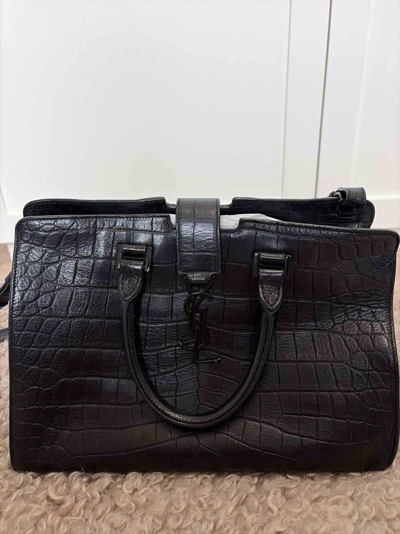 YSL Saint Laurent Monogram Cabas Bag （分類：手袋及銀包）位於 Hong Kong。 由 luxurystyles 提交（商品編號 1457950236，圖片 1）。簡介： Product Information This elegant Cabas tote from Saint Laurent is ideal for everyday use. Crafted from croc-embossed leather, the bag is detailed with a black-tone YSL motif snap closure, dual-rolled handles and protective metal feet at the bottom. It opens to a spacious suede-lined interior that houses a well-sized compartment to hold all you