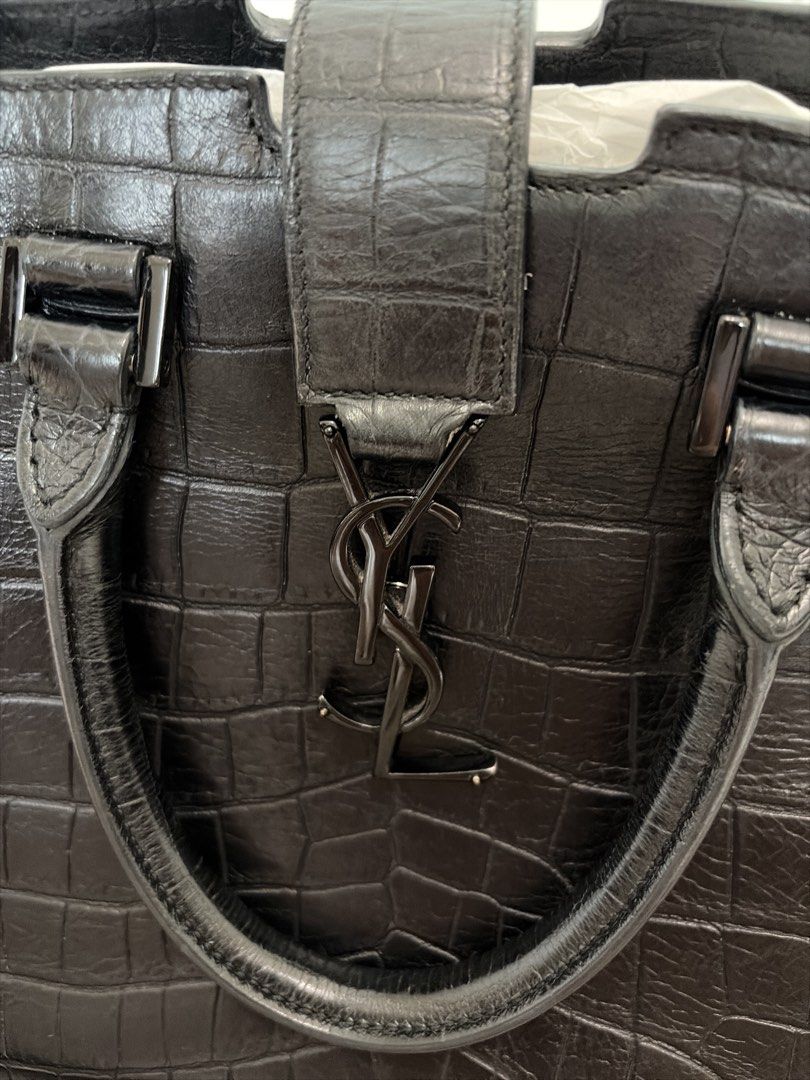 YSL Saint Laurent Monogram Cabas Bag （分類：手袋及銀包）位於 Hong Kong。 由 luxurystyles 提交（商品編號 1457950236，圖片 3）。簡介： Product Information This elegant Cabas tote from Saint Laurent is ideal for everyday use. Crafted from croc-embossed leather, the bag is detailed with a black-tone YSL motif snap closure, dual-rolled handles and protective metal feet at the bottom. It opens to a spacious suede-lined interior that houses a well-sized compartment to hold all you