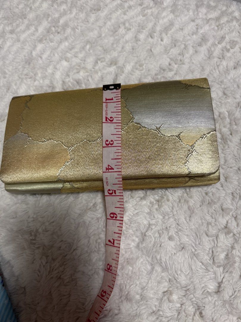 2027 Gold Brocade Clutch Bag with Abstract Pattern (Category: Clutches) located in Silang. Submitted by sari2bilina (Listing ID 1458231128, Image 1). Description: - Stunning gold brocade clutch bag - Features a beautiful abstract pattern in gold and silver tones - Interior lined in gold fabric - Includes a convenient pleated compartment - Secure snap button closure - Approximate dimensions: 8 inches long x 4 inches tall - Ideal for evening wear a