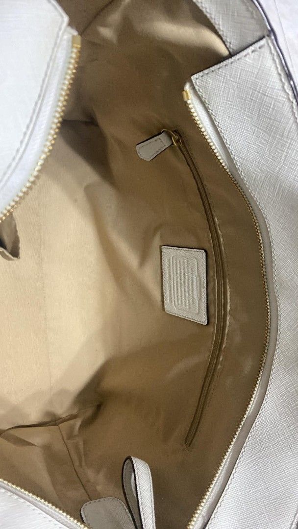 Coach White Saffiano Leather Tote Bag (Category: Luxury Bags & Wallets) located in Angono. Submitted by denflrntz (Listing ID 1458237731, Image 3). Description: - White Coach tote bag bought for Php 15k (Duty Free - Korea) - Saffiano leather exterior - Gold hardware details - Interior zip pocket - Small black stain in the back (visible in last photo) - Clean interior - Spacious design - Slightly negotiable.