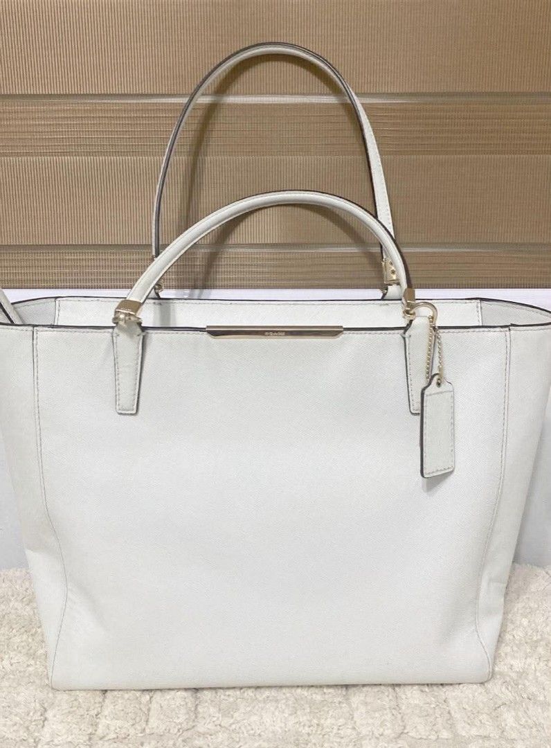Coach White Saffiano Leather Tote Bag (Category: Luxury Bags & Wallets) located in Angono. Submitted by denflrntz (Listing ID 1458237731, Image 1). Description: - White Coach tote bag bought for Php 15k (Duty Free - Korea) - Saffiano leather exterior - Gold hardware details - Interior zip pocket - Small black stain in the back (visible in last photo) - Clean interior - Spacious design - Slightly negotiable.