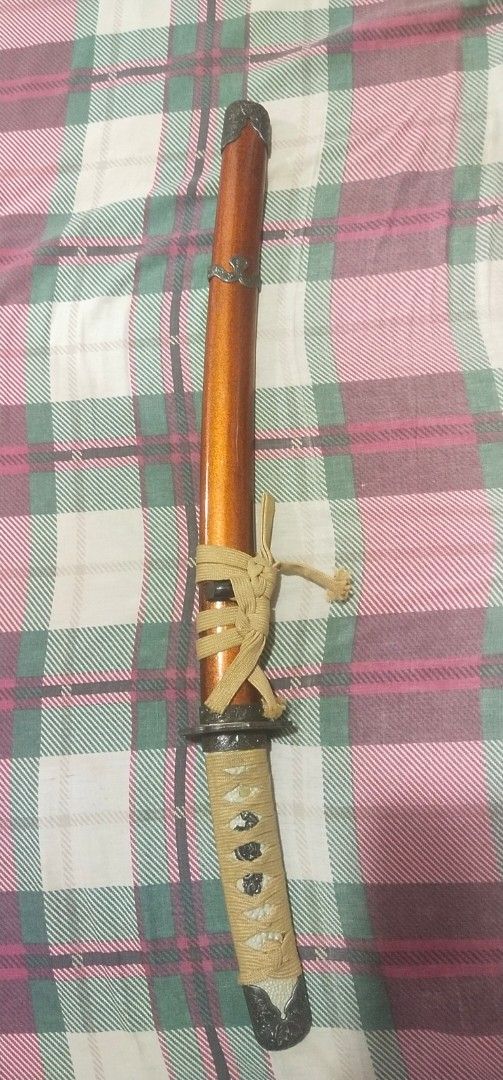 Decorative Katana Sword with Scabbard (Category: Vintage Collectibles) located in Muntinlupa City. Submitted by grayfox05 (Listing ID 1458149960, Image 1). Description: - Decorative katana sword, ideal for display. - Features a glossy orange finished wooden scabbard. - Handle is wrapped in tan cord for a comfortable grip. - Blade includes intricate decorative etching. - Comes with a tie to securely fasten the sword in the scabbard. meet up bayana