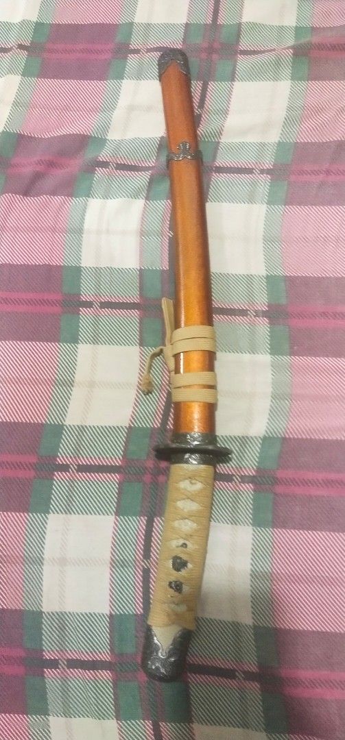 Decorative Katana Sword with Scabbard (Category: Vintage Collectibles) located in Muntinlupa City. Submitted by grayfox05 (Listing ID 1458149960, Image 2). Description: - Decorative katana sword, ideal for display. - Features a glossy orange finished wooden scabbard. - Handle is wrapped in tan cord for a comfortable grip. - Blade includes intricate decorative etching. - Comes with a tie to securely fasten the sword in the scabbard. meet up bayana