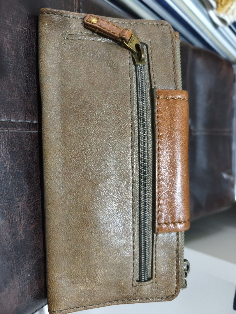 Fossil Leather Wallet (Category: Wallets & Card holders) located in Quezon City. Submitted by tajima (Listing ID 1458159209, Image 3). Description: - Genuine brown leather Fossil wallet - Secure turn-lock closure on front flap - Convenient zip pocket on the back - Multiple interior card slots - Clear ID window for easy access - Unique key pattern lining - Shows some signs of wear, still fully functional.