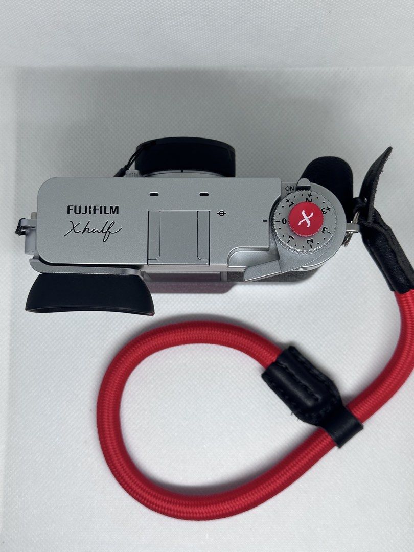 Fujifilm -Xhalf (Category: Cameras) located in Quezon City. Submitted by ronniecar37103 (Listing ID 1458137782, Image 3). Description: - Fujifilm X-Half camera - Type: Point-and-shoot - Color: Silver and black - Condition: Good, pre-owned - Includes: Red wrist strap.