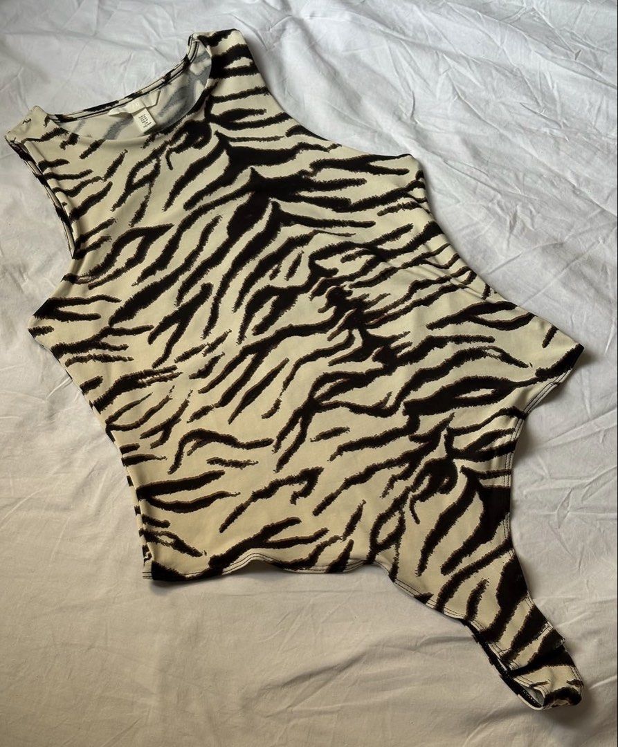 H&M Zebra Print Tank Top (Category: Sleeveless) located in Manila. Submitted by thedailythreadclub (Listing ID 1458100440, Image 1). Description: - H&M cream and black zebra print tank top - Sleeveless with a high neckline - Stretchy material for comfort - Unique asymmetrical hemline - Versatile for layering or wearing alone - Pairs well with jeans or shorts -Orig price 1k.