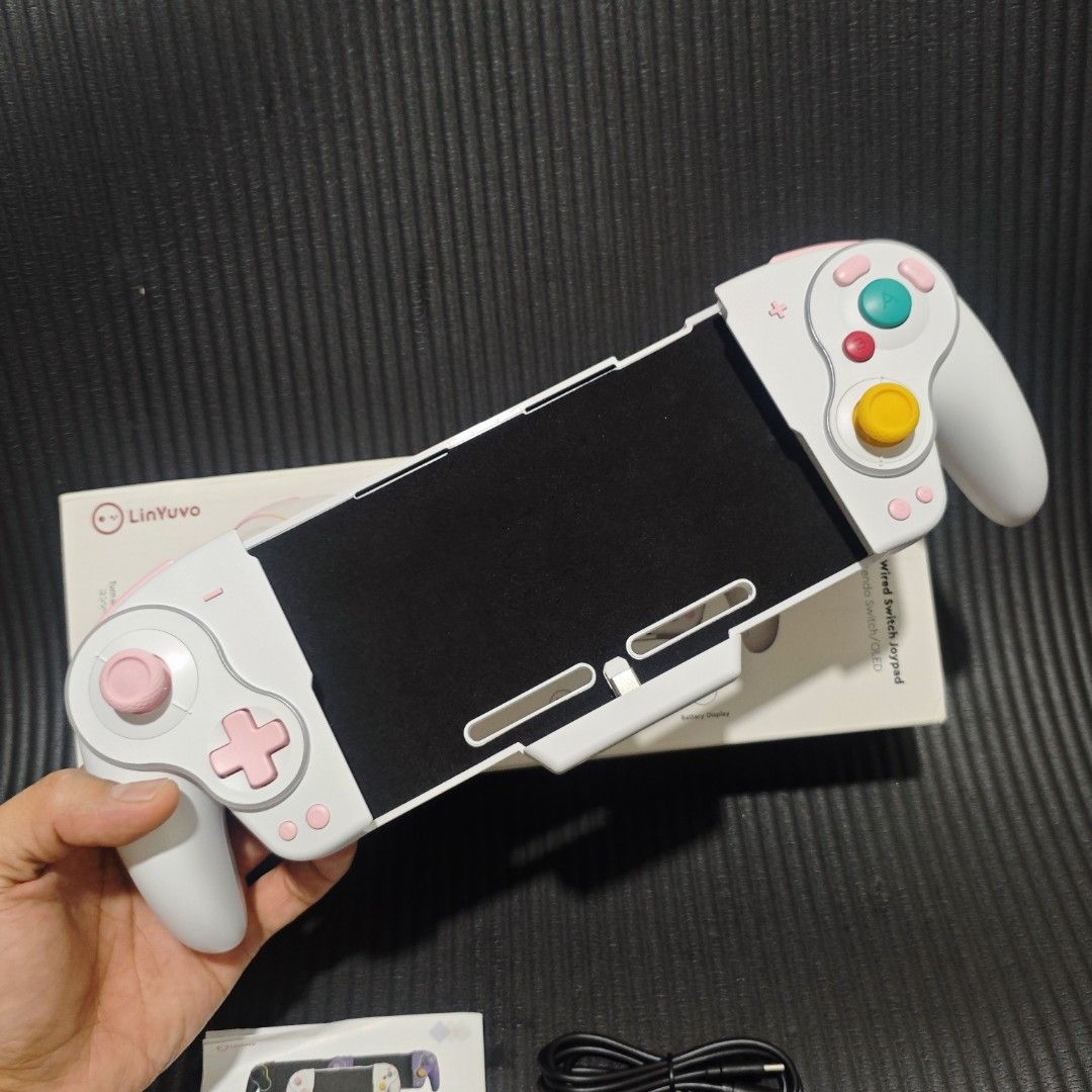 LinYuvo KS63 RGB Wireless Controller Gamepad (Category: Controllers) located in Quezon City. Submitted by shopme_gadget30 (Listing ID 1458262576, Image 3). Description: Heavily inspired by the classic Nintendo GameCube controller design, featuring the recognizable oversized green 'A' button, red 'B' button, and a distinctive yellow C-stick analog grip.Ergonomic One-Piece Form Factor: Built as a single continuous dock frame that wraps securely aro