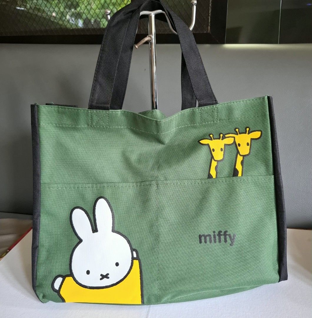 Miffy Green Tote Bag with Giraffe Pockets (Category: Tote Bags) located in Don Carlos. Submitted by PphiXi_Finds (Listing ID 1458251539, Image 1). Description: Cute green tote bag featuring Miffy and two giraffes. Has front pockets for easy access. Great for shopping or carrying everyday essentials. Handles are black and sturdy. Measures about 15 inches wide..