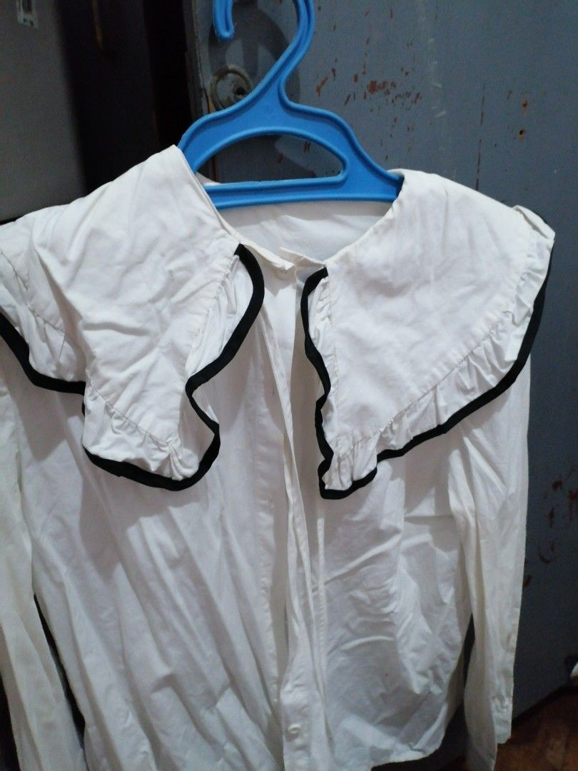 White Blouse with Black Trim Peter Pan Collar (Category: Blouses) located in Manila. Submitted by llouisevilla (Listing ID 1458189774, Image 1). Description: - White long-sleeved blouse - Features a large Peter Pan collar with ruffled edges and black trim - Button-up front - Cute and stylish design - Versatile for dressing up or down.