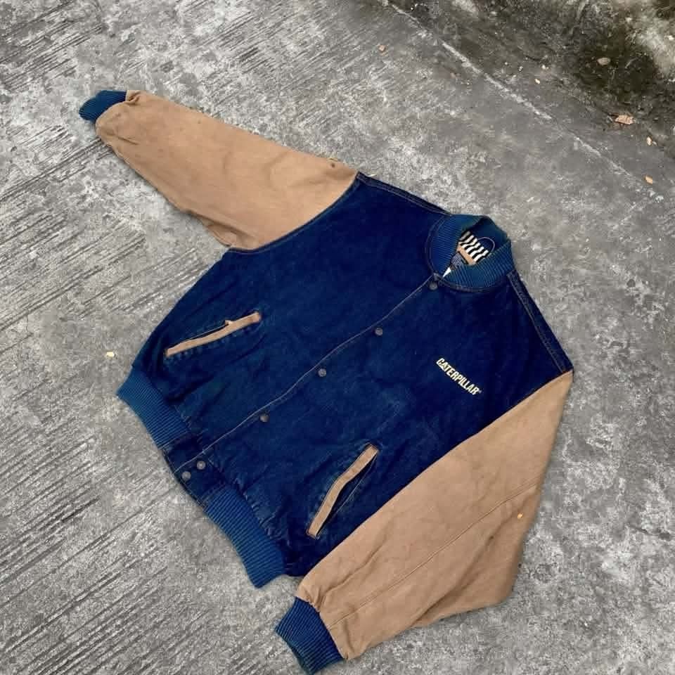 CATERPILLAR DENIM JACKET (Category: Coats, Jackets and Outerwear) located in Imus. Submitted by whiteboy_nik (Listing ID 1458419420, Image 2). Description: - Brand: Caterpillar - Type: Denim Jacket with contrasting sleeves - Design: Varsity style with embroidered logo - Color: Blue denim with tan sleeves - Size: Free Size - Condition: Great, pre-loved item.