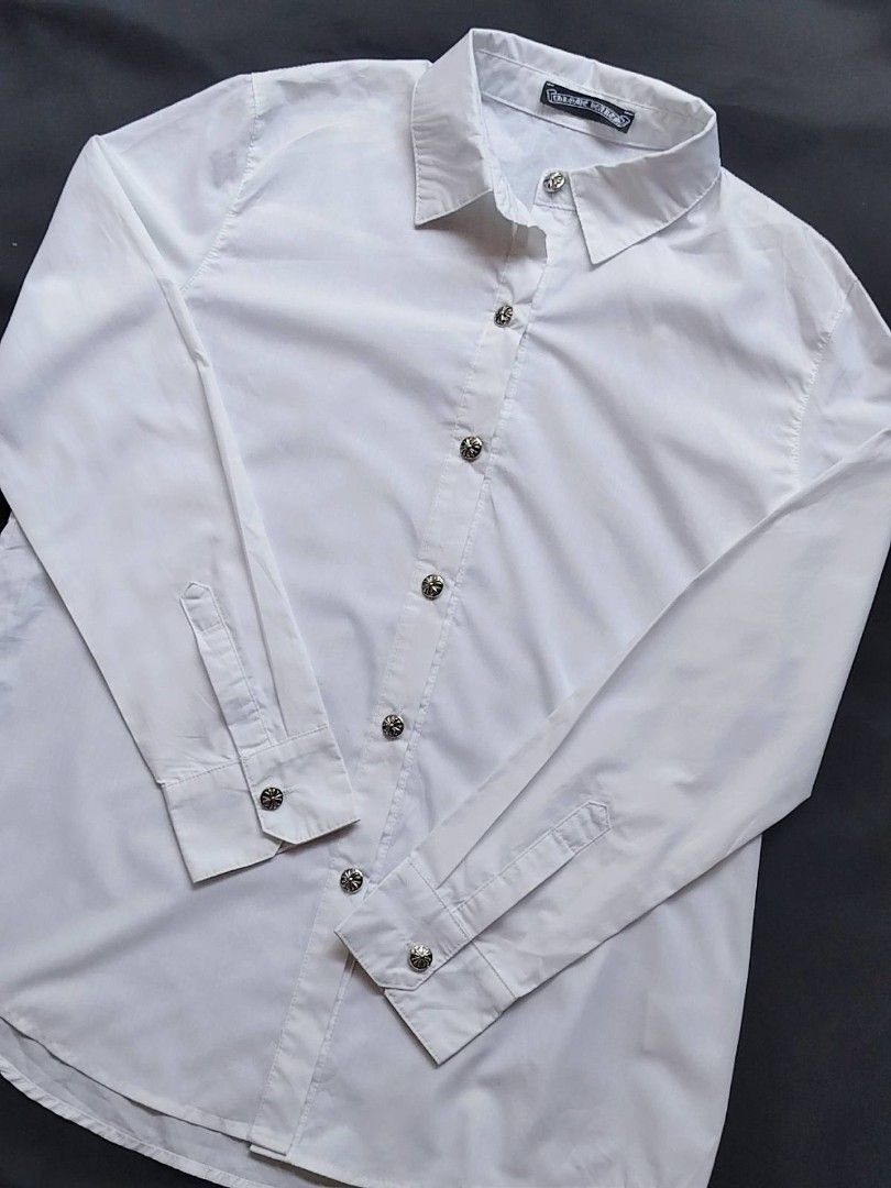 Chrome Hearts White Button Up Shirt (Category: Tshirts & Polo Shirts ) located in Manila. Submitted by ravieollie (Listing ID 1458379384, Image 1). Description: - Authentic Chrome Hearts white button-up shirt - Unique cross-shaped buttons for a distinctive look - Classic collar and long sleeves with button cuffs - Effortlessly dress up or down for any occasion - Sharp and stylish addition to your wardrobe.