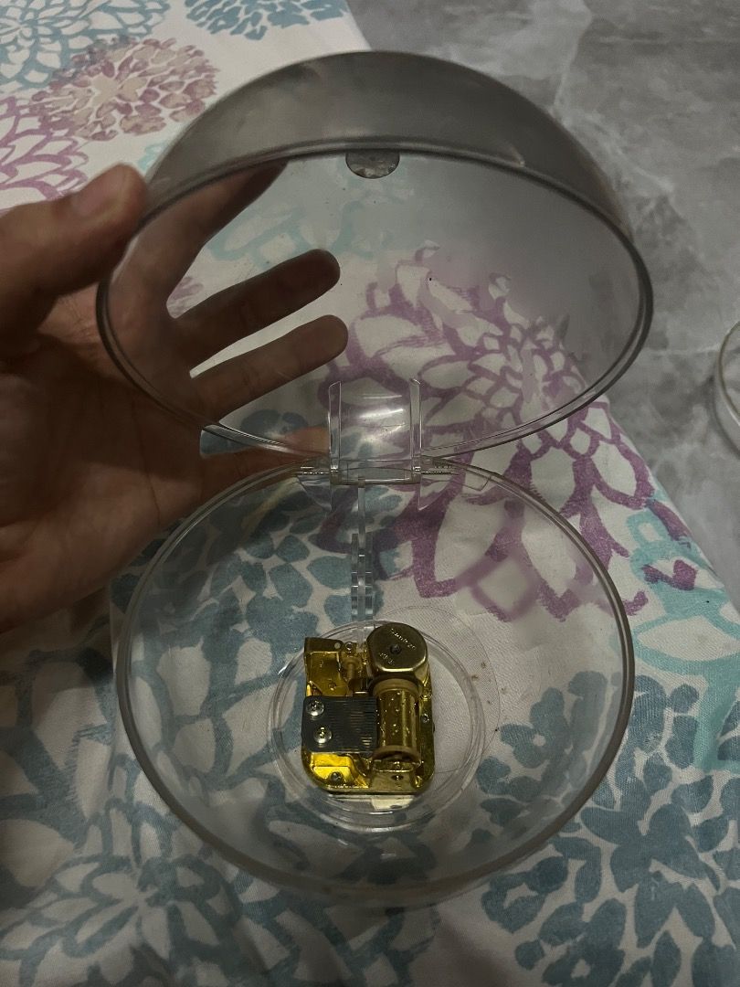 Clear Music Box Mechanism with Gold Components (Category: Accessory Holder, Box & Organizers) located in Caloocan City. Submitted by joshualari57872 (Listing ID 1458345975, Image 2). Description: - Gold-colored music box mechanism - Housed in a clear plastic casing - Features a clear, hinged plastic lid - Inner workings are visible for a unique aesthetic - Ideal for DIY crafts, custom music boxes, or decorative projects Offer na kayo.