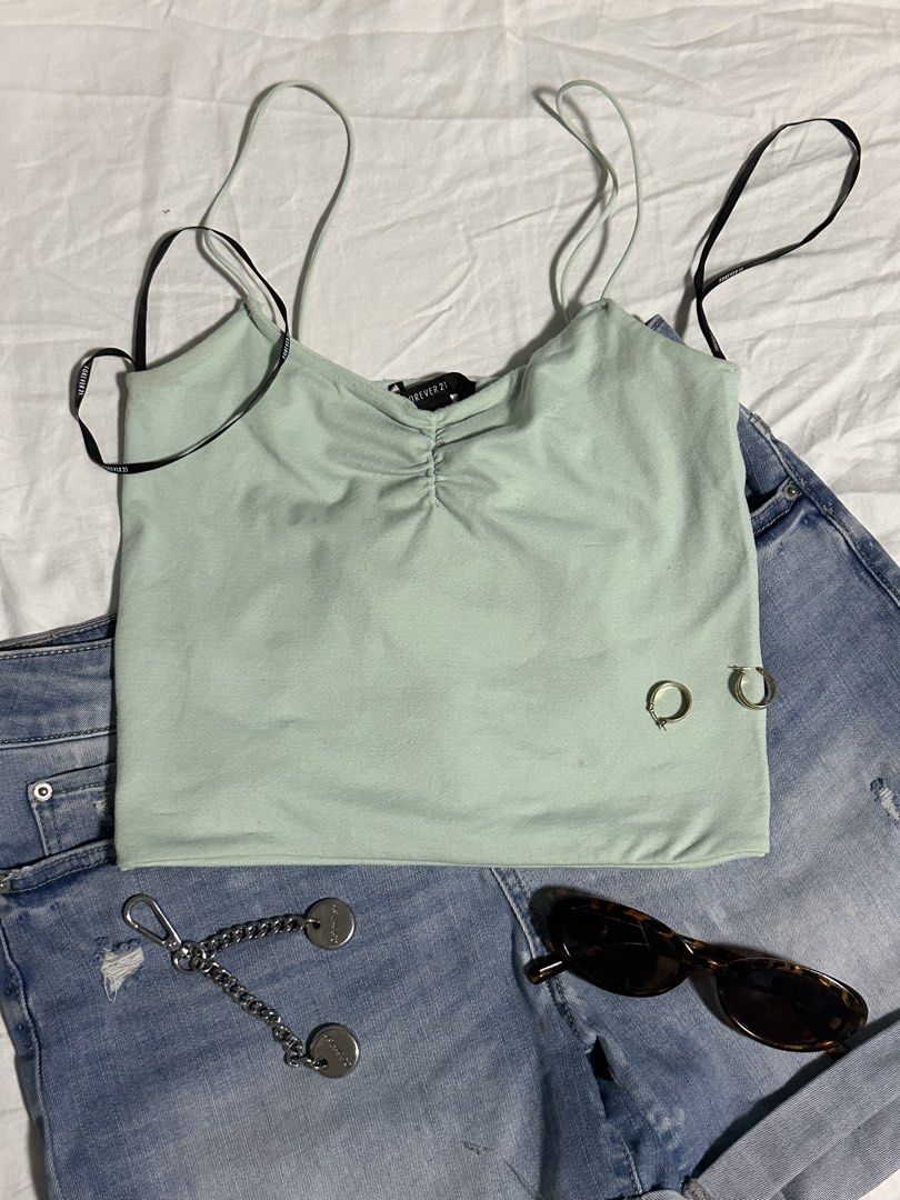 Forever 21 Ruched Camisole Crop Top (Category: Sleeveless) located in Subic. Submitted by iyah.s_ (Listing ID 1458427379, Image 1). Description: - Light mint green camisole crop top - Brand: Forever 21 - Features ruched front - Versatile for casual outings or nights out - Pairs well with denim shorts.