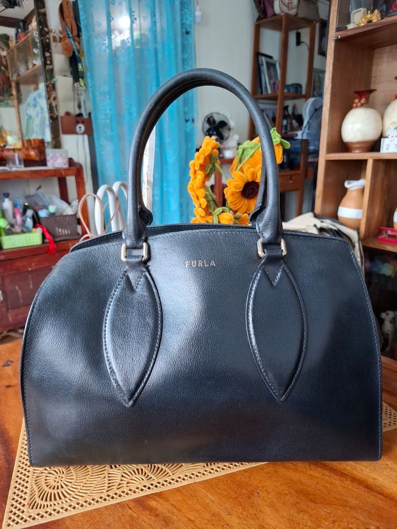 Furla Black Leather Top Handle Handbag (Category: Luxury Bags & Wallets) located in Libon. Submitted by jaladzarmi80045 (Listing ID 1458354063, Image 1). Description: - Classic black leather handbag by Furla - Features a comfortable top handle - Secure zip closure - Elegant gold hardware details - Spacious interior for all your essentials - Versatile for daily use or special occasions -8/10 condition -detached 1 slingslot (see pic).