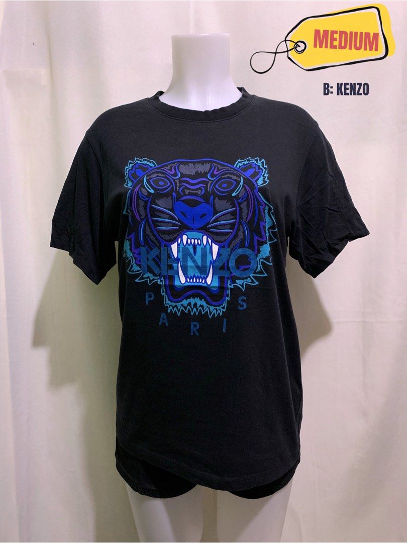 Kenzo Paris Tiger Print T-Shirt Medium (Category: Tshirts & Polo Shirts ) located in Cardona. Submitted by rmlyn1998 (Listing ID 1458389733, Image 1). Description: - Authentic Black Kenzo T-Shirt - Iconic Tiger Print with Blue & Purple Accents - 'PARIS' detail below the tiger graphic - Size: Medium - Ideal for everyday casual wear.