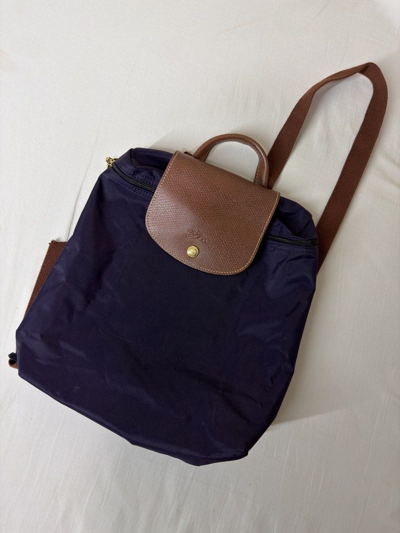 Longchamp Le Pliage Backpack Purple (Category: Luxury Bags & Wallets) located in Angeles City. Submitted by muse_archive (Listing ID 1458380212, Image 1). Description: - Longchamp purple nylon backpack - Brown leather trim - Top handle - Adjustable shoulder straps - Zipper closure - Front flap with snap button - Spacious interior - Ideal for everyday use or travel.