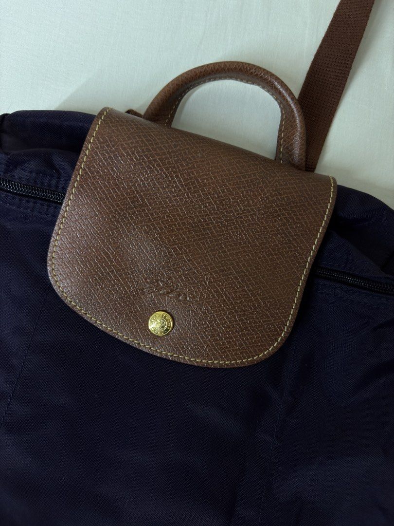 Longchamp Le Pliage Backpack Purple (Category: Luxury Bags & Wallets) located in Angeles City. Submitted by muse_archive (Listing ID 1458380212, Image 2). Description: - Longchamp purple nylon backpack - Brown leather trim - Top handle - Adjustable shoulder straps - Zipper closure - Front flap with snap button - Spacious interior - Ideal for everyday use or travel.