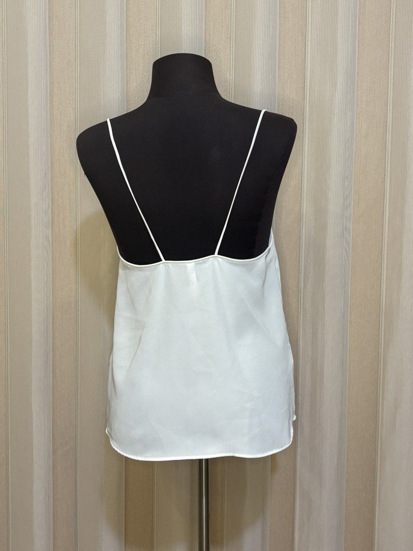 Mango White Camisole Top (Category: Sleeveless) located in Angeles City. Submitted by shopbettina (Listing ID 1458408992, Image 2). Description: - White camisole top from Mango Suit - Features thin spaghetti straps - Ruched detail at the bust - Small mark on fabric (shown in last photo) - Versatile for layering or wearing alone.