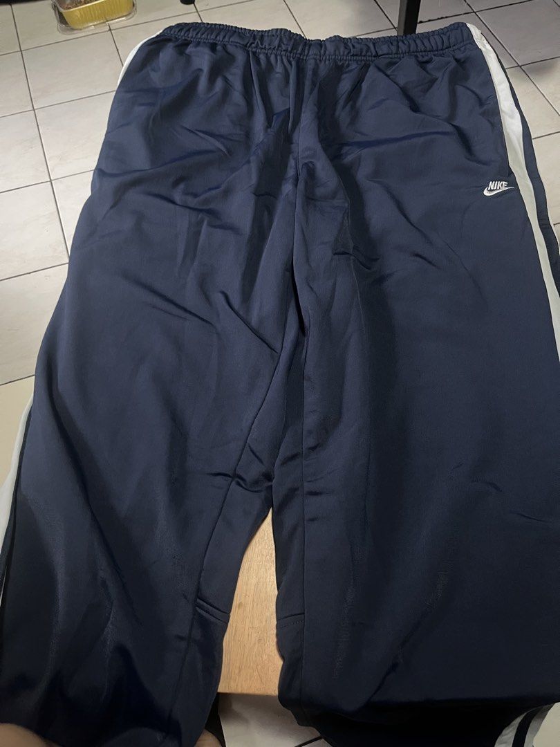 Nike track pants (Category: Joggers) located in Quezon City. Submitted by shopaholics.31 (Listing ID 1458310281, Image 1). Description: The highlighted item is a pair of vintage Nike side-stripe track pants in navy blue and white. Color Scheme: Deep midnight navy blue with stark contrast white side stripes.Branding: Classic mini Nike Swoosh text logo embroidered in white on the left thigh. Design Details: White dual-stripe panelling running down 