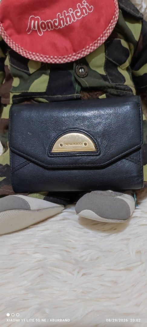 Nina Ricci wallet (Category: Wallets & Card holders) located in Makati City. Submitted by yerbua103 (Listing ID 1458423987, Image 1). Description: This is a vintage Nina Ricci with black textured leather flap wallet featuring a gold-tone half-moon metal hardware logo plaque on the front snap closure. Manage your expectations as you're buying a preloved/ukay wallet. Disclaimer: No copyright/ infringement is intended. the brand belongs to the right