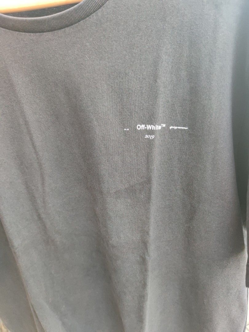 Off-White "Main Label" 2019 Black Graphic T-Shirt (Category: Tshirts & Polo Shirts ) located in Pasig City. Submitted by ftwind (Listing ID 1458314290, Image 3). Description: - Authentic Off-White 'Main Label' Graphic Tee - Year: 2019 - Iconic Off-White arrow logo prominently displayed on the back - Subtle 'Off-White' and 'spring-summer' text branding on the front - Designed to represent the 'grey area between black and white' .