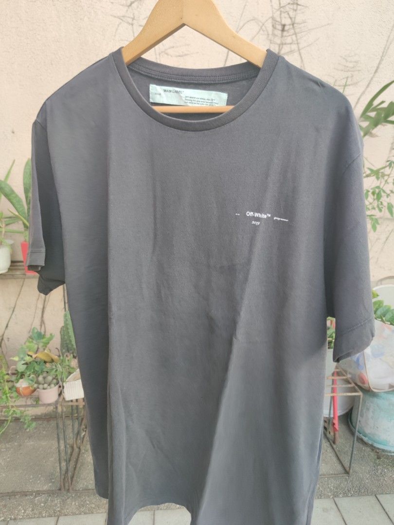 Off-White "Main Label" 2019 Black Graphic T-Shirt (Category: Tshirts & Polo Shirts ) located in Pasig City. Submitted by ftwind (Listing ID 1458314290, Image 2). Description: - Authentic Off-White 'Main Label' Graphic Tee - Year: 2019 - Iconic Off-White arrow logo prominently displayed on the back - Subtle 'Off-White' and 'spring-summer' text branding on the front - Designed to represent the 'grey area between black and white' .