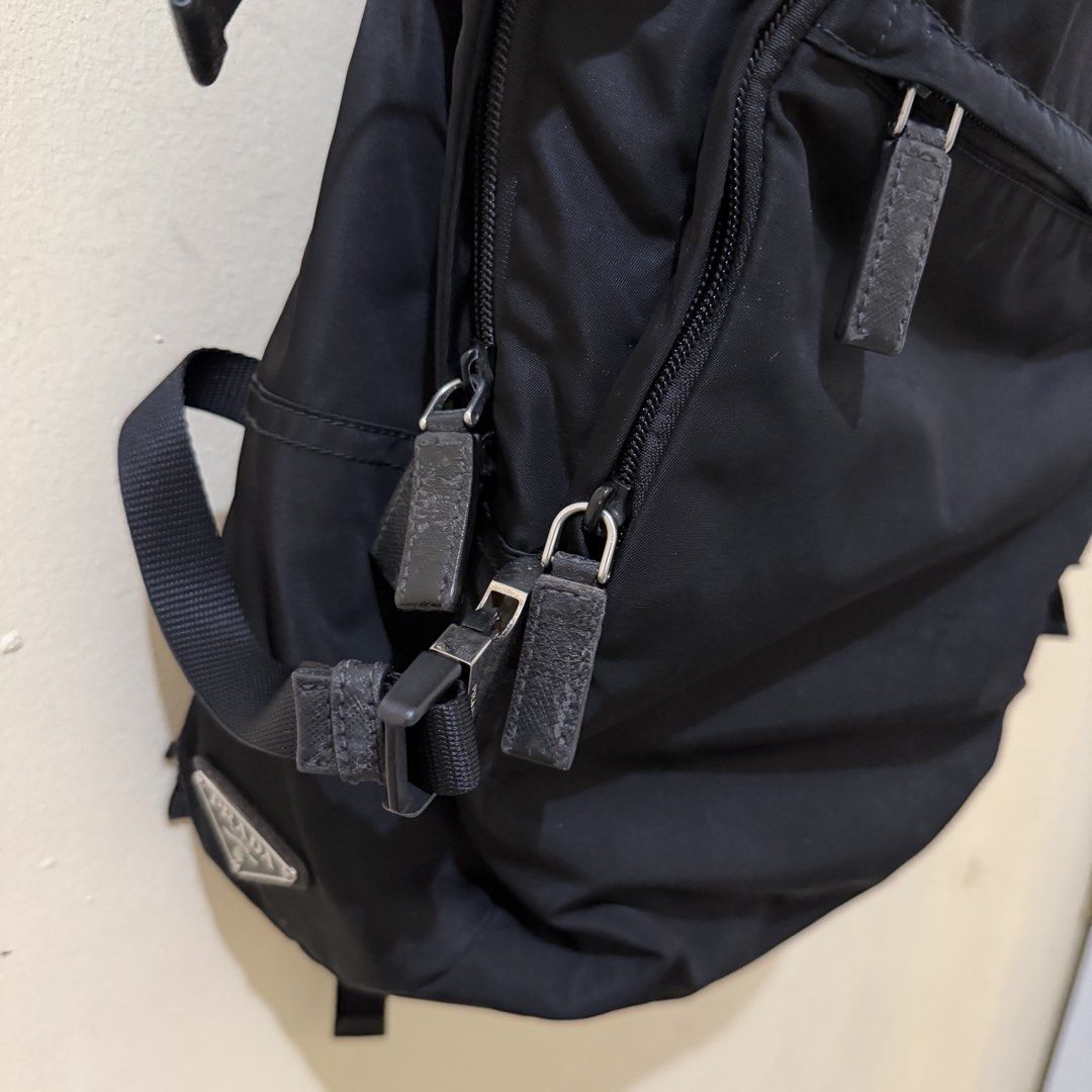 Prada Nylon Backpack Black (Category: Luxury Bags & Wallets) located in Tiwi. Submitted by demabubut (Listing ID 1458409684, Image 3). Description: - Authentic Black Prada Backpack - Made of durable nylon material - Multiple zip pockets for organized storage - Secure buckle closures - Iconic Prada logo prominently displayed on the front - Minor wear on zipper pulls and buckles, adding character - Ideal for everyday use and travel.