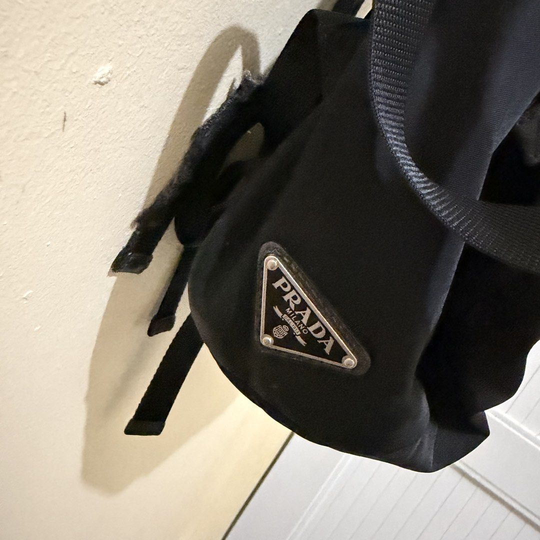 Prada Nylon Backpack Black (Category: Luxury Bags & Wallets) located in Tiwi. Submitted by demabubut (Listing ID 1458409684, Image 2). Description: - Authentic Black Prada Backpack - Made of durable nylon material - Multiple zip pockets for organized storage - Secure buckle closures - Iconic Prada logo prominently displayed on the front - Minor wear on zipper pulls and buckles, adding character - Ideal for everyday use and travel.