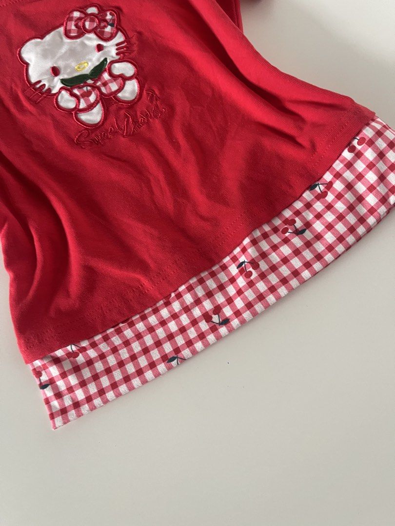 Red Hello Kitty Off-Shoulder T-Shirt with Gingham Trim (Category: Shirts) located in Cavite. Submitted by devilourea (Listing ID 1458334209, Image 3). Description: - Adorable red t-shirt featuring an embroidered Kitty graphic. - Delicate lace trim along the neckline for a touch of charm. - Stylish gingham strap adds a playful detail. - Hemline showcases a red and white gingham pattern with cute cherry accents. - A fun and playful top perfect for 