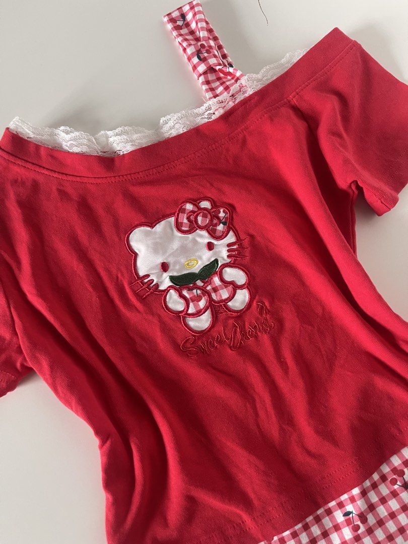 Red Hello Kitty Off-Shoulder T-Shirt with Gingham Trim (Category: Shirts) located in Cavite. Submitted by devilourea (Listing ID 1458334209, Image 2). Description: - Adorable red t-shirt featuring an embroidered Kitty graphic. - Delicate lace trim along the neckline for a touch of charm. - Stylish gingham strap adds a playful detail. - Hemline showcases a red and white gingham pattern with cute cherry accents. - A fun and playful top perfect for 