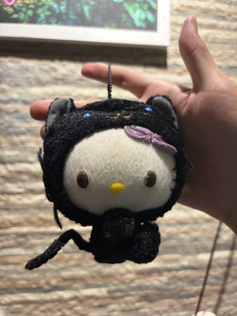 Sanrio Hello Kitty Black Cat Plush Keychain 2005 (Category: Plushies & Soft Toys) located in Makati City. Submitted by squishycorner (Listing ID 1458408758, Image 1). Description: - Adorable Kitty plush keychain - Dressed as a black cat with a purple bow and yellow beak - Authentic Sanrio merchandise from 2005 - Features a metal chain for easy attachment to bags or keys - A must-have for any Kitty enthusiast!.