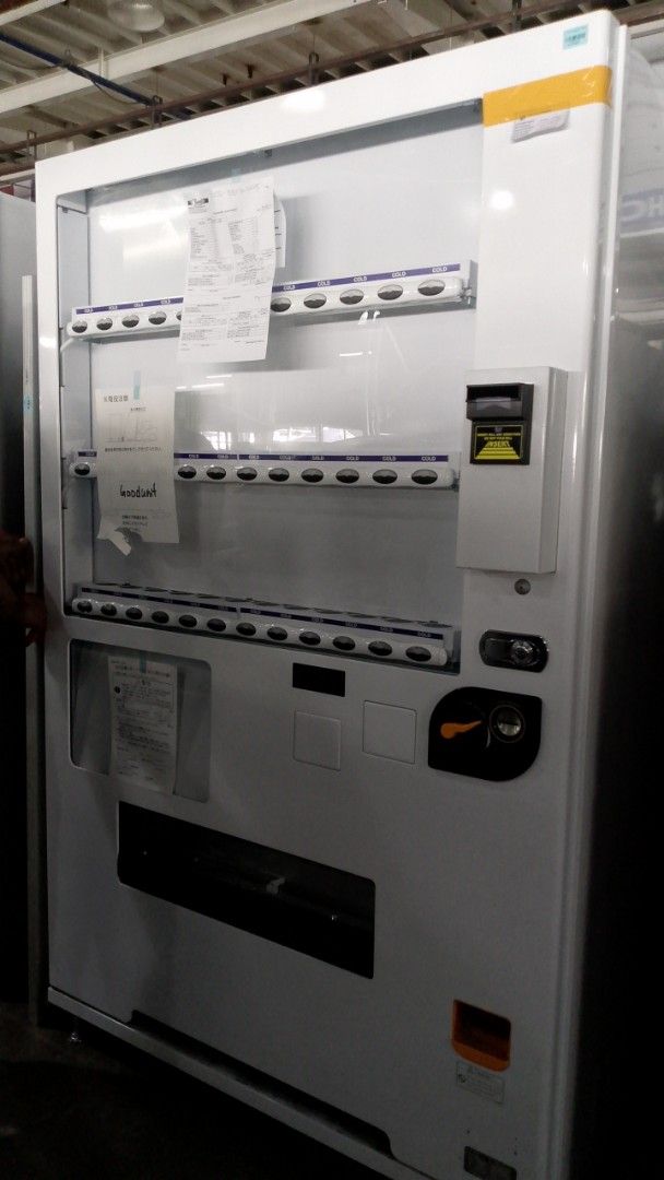 White Vending Machine - Beverage Dispenser (Category: Refrigerators and Freezers) located in Manila. Submitted by silentturtle.e8012b (Listing ID 1458351900, Image 1). Description: - White vending machine - Multiple shelves for drinks - Features coin slot and dispensing area - Ideal for business or large events - Wrapped in plastic, ready for transport or storage - Feel free to ask questions!.