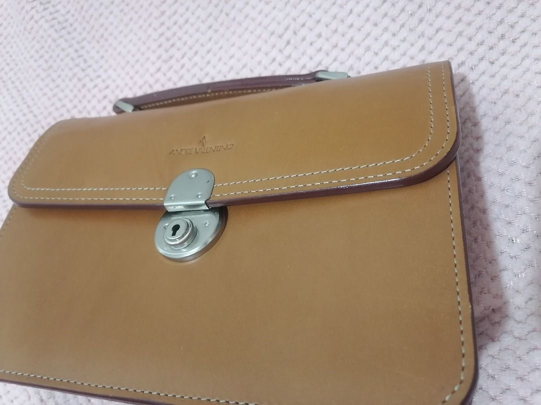 andre valentino (Category: Luxury Bags & Wallets) located in Paranaque City. Submitted by neveahthrift (Listing ID 1453584375, Image 3). Description: Brand: Andre Valentino (Established since 1996)Item Type: Vintage Structured Organizer Bag / Top-Handle ClutchEstimated Production Era: Late 1990s to Early 2000s (Based on the signature minimalist typography stamp and the vintage frame build)Material: Authentic, premium vegetable-tanned smooth tan/c