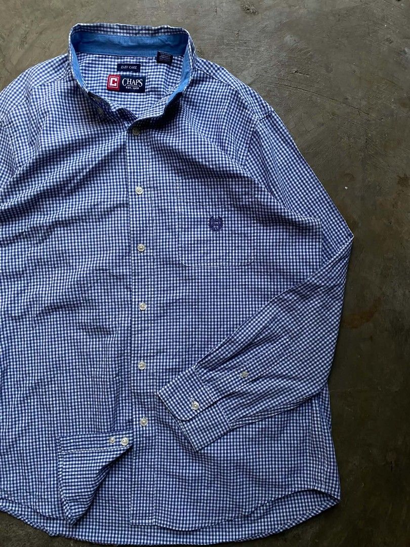 Chaps Easy Care Gingham Button Down Shirt (Category: Tshirts & Polo Shirts ) located in Cabanatuan. Submitted by vivian_nicole_03 (Listing ID 1453535791, Image 2). Description: - Classic blue and white gingham pattern - Brand: Chaps - Style: Button-down shirt - Neckline: Collared - Closure: Button - Features: Chest pocket with embroidered Chaps logo - Fabric: Easy care, suitable for everyday wear - Size: Medium (M).