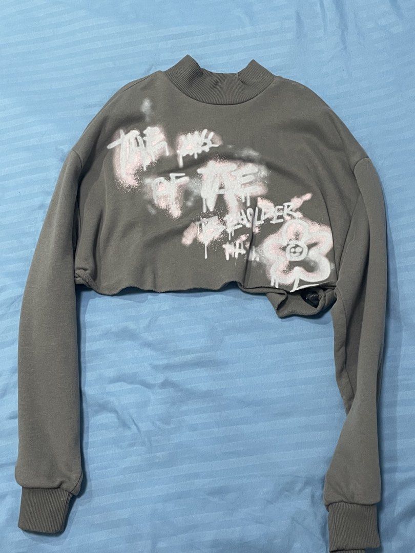 Divided Grey Cropped Sweatshirt with Graffiti Print (Category: Longsleeves) located in Marikina City. Submitted by flutterchi (Listing ID 1453584234, Image 1). Description: - Grey cropped sweatshirt from Divided - Features a graffiti-style print with pink and white details - Mock neck and long sleeves - Raw hem for a trendy look - Super cropped fit, perfect with high-waisted bottoms.