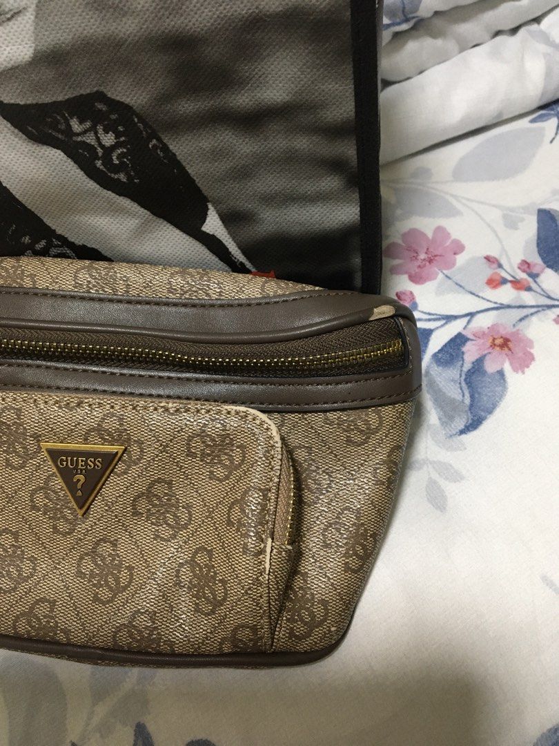 Guess Monogram Fanny Pack Belt Bag (Category: Cross-body Bags) located in Quezon City. Submitted by simple_precious (Listing ID 1453471186, Image 2). Description: - Brown Guess fanny pack with signature monogram print. - Features gold hardware and zipper details. - Adjustable strap with a secure gold buckle. - Interior includes a main compartment and a small pocket. - Shows minor wear on the corner, as pictured. - Ideal for keeping your essential