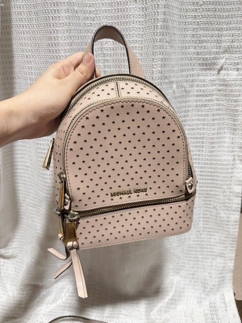 Michael Kors Pink Rhea Mini Star Backpack (Category: Backpacks) located in Manila. Submitted by prelovedbyfe08 (Listing ID 1453539058, Image 2). Description: - Michael Kors backpack in a lovely light pink color. - Features a stylish all-over star perforation design. - Accented with elegant gold-tone hardware and zippers. - Includes a versatile detachable crossbody strap. - Ideal for everyday adventures or your next getaway. Flaws: May stains and 