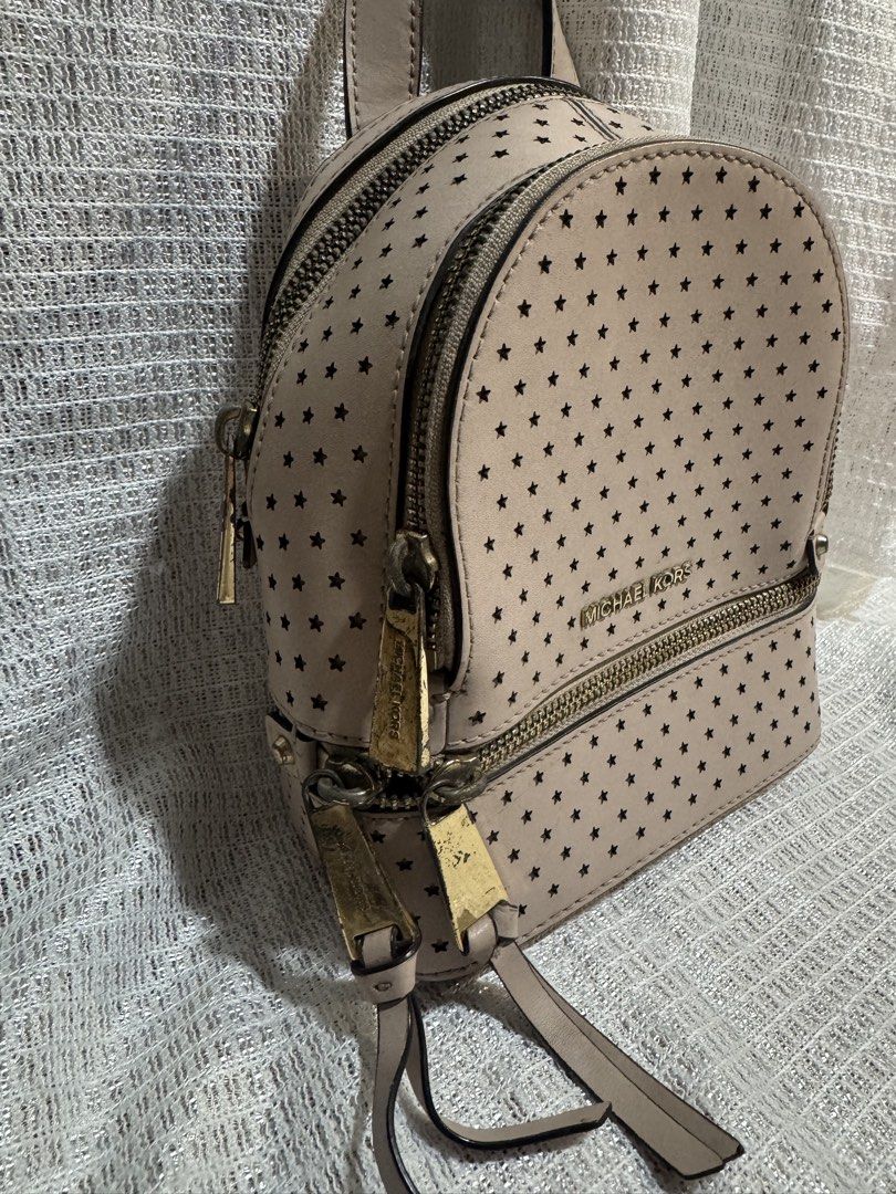 Michael Kors Pink Rhea Mini Star Backpack (Category: Backpacks) located in Manila. Submitted by prelovedbyfe08 (Listing ID 1453539058, Image 3). Description: - Michael Kors backpack in a lovely light pink color. - Features a stylish all-over star perforation design. - Accented with elegant gold-tone hardware and zippers. - Includes a versatile detachable crossbody strap. - Ideal for everyday adventures or your next getaway. Flaws: May stains and 